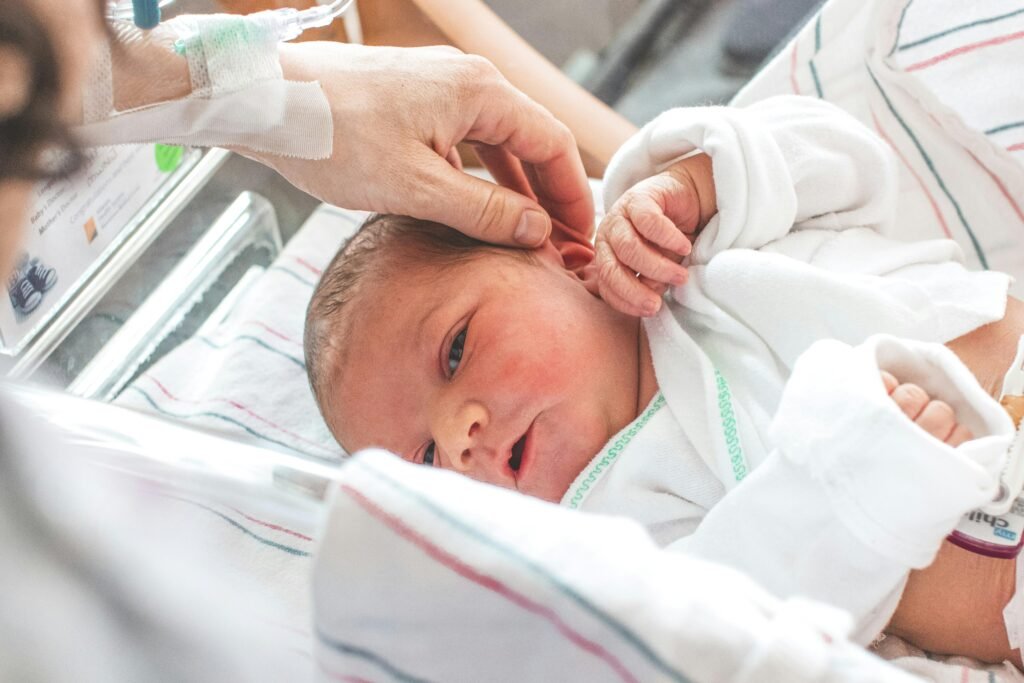 A loving hand touches a newborn baby lying peacefully in a hospital setting.