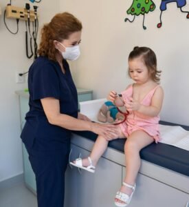 A child is examined by a nurse in a pediatrician's office, emphasizing gentle healthcare.